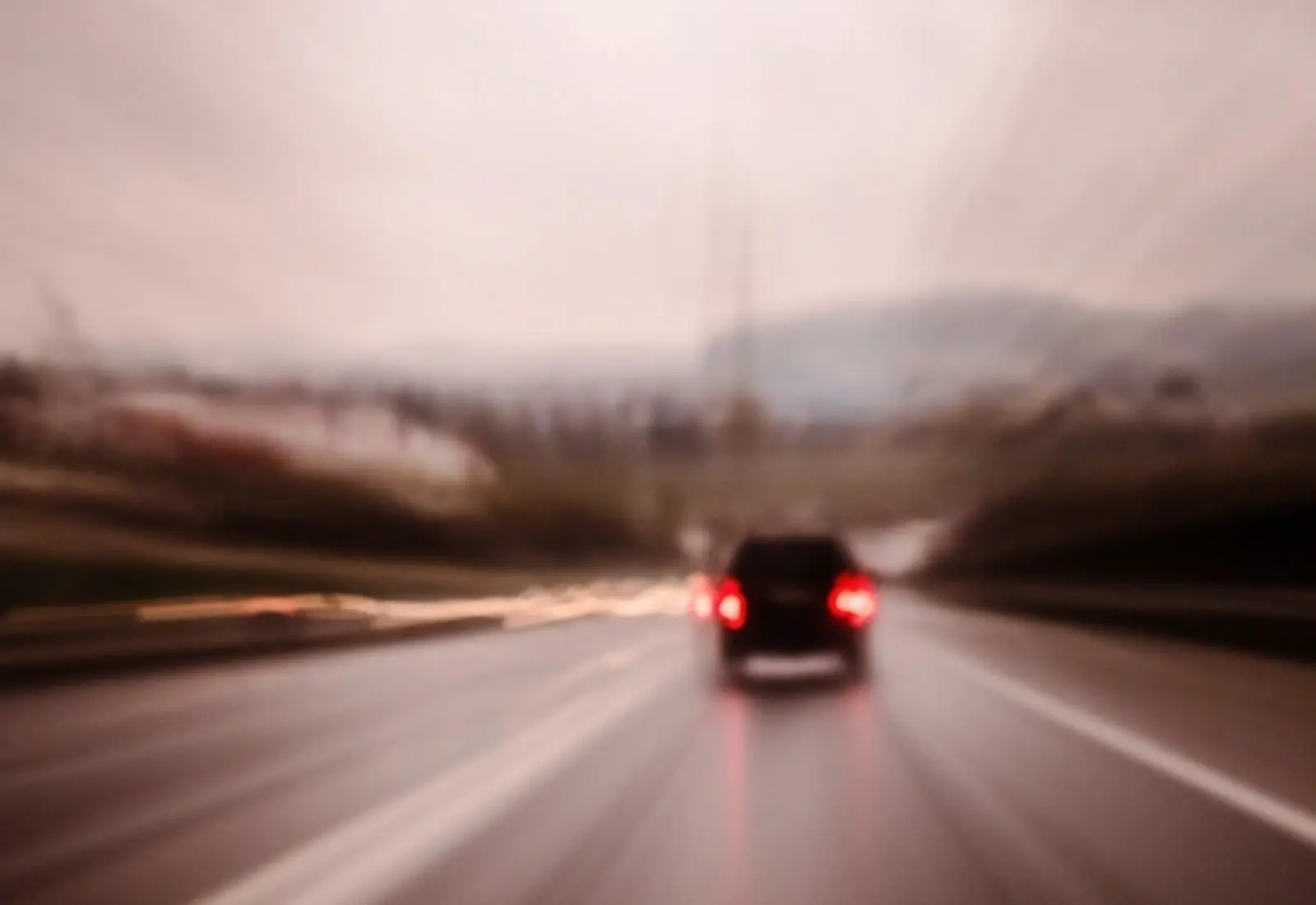 Coche en marcha por una carretera con las luces traseras encendidas